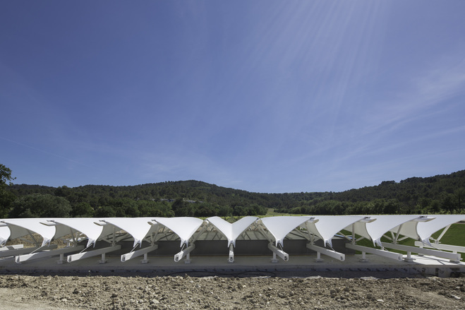 PVC-coated polyester membrane sails tensioned over steel arches and cable valleys